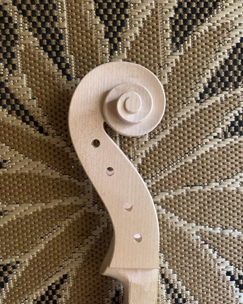 Violoncelo parcialmente montado com cordas ou cavalete visível.